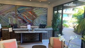 A modern lobby with a reception desk, seating area, and large abstract paintings. - Amazing Ocean/Mountain Views. Beautifully.One From Oceanfront (Lahaina)