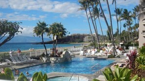 A pool area with lounge chairs and palm trees, overlooking a beach. - Amazing Ocean/Mountain Views. Beautifully.One From Oceanfront (Lahaina)
