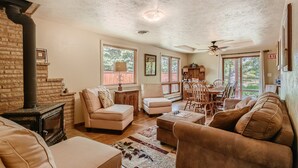 A cozy living room with a fireplace, comfortable seating, and large windows.