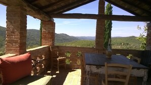 Ein rustikaler Außenbereich mit Tisch und Stühlen, mit Blick auf eine Berglandschaft.