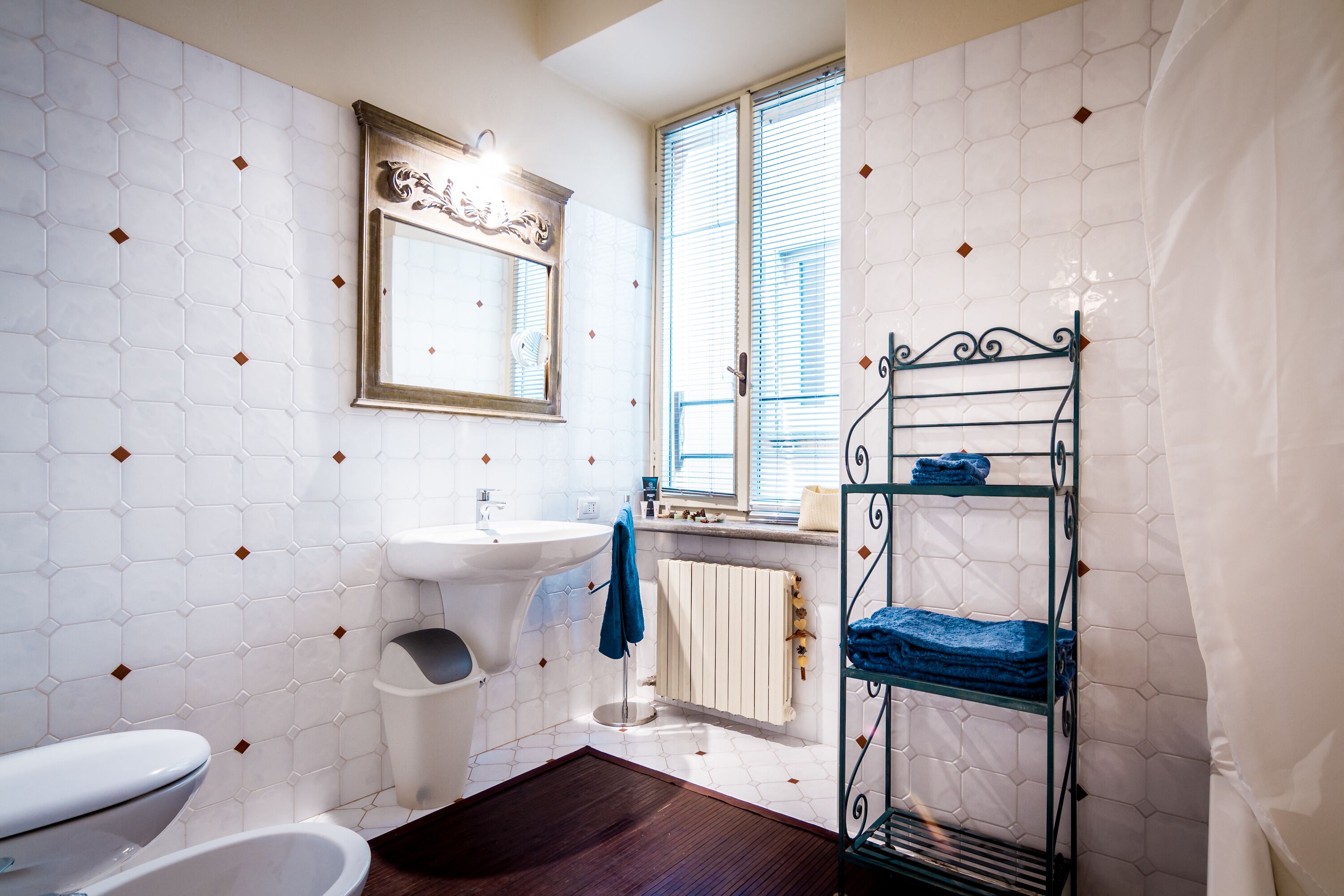 A bathroom with a white sink, toilet, and a metal rack with towels.