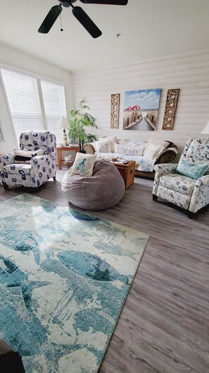 Relax in this stylish living room with a plush bean bag chair, armchairs, and a sofa, surrounded by artwork and a large rug.