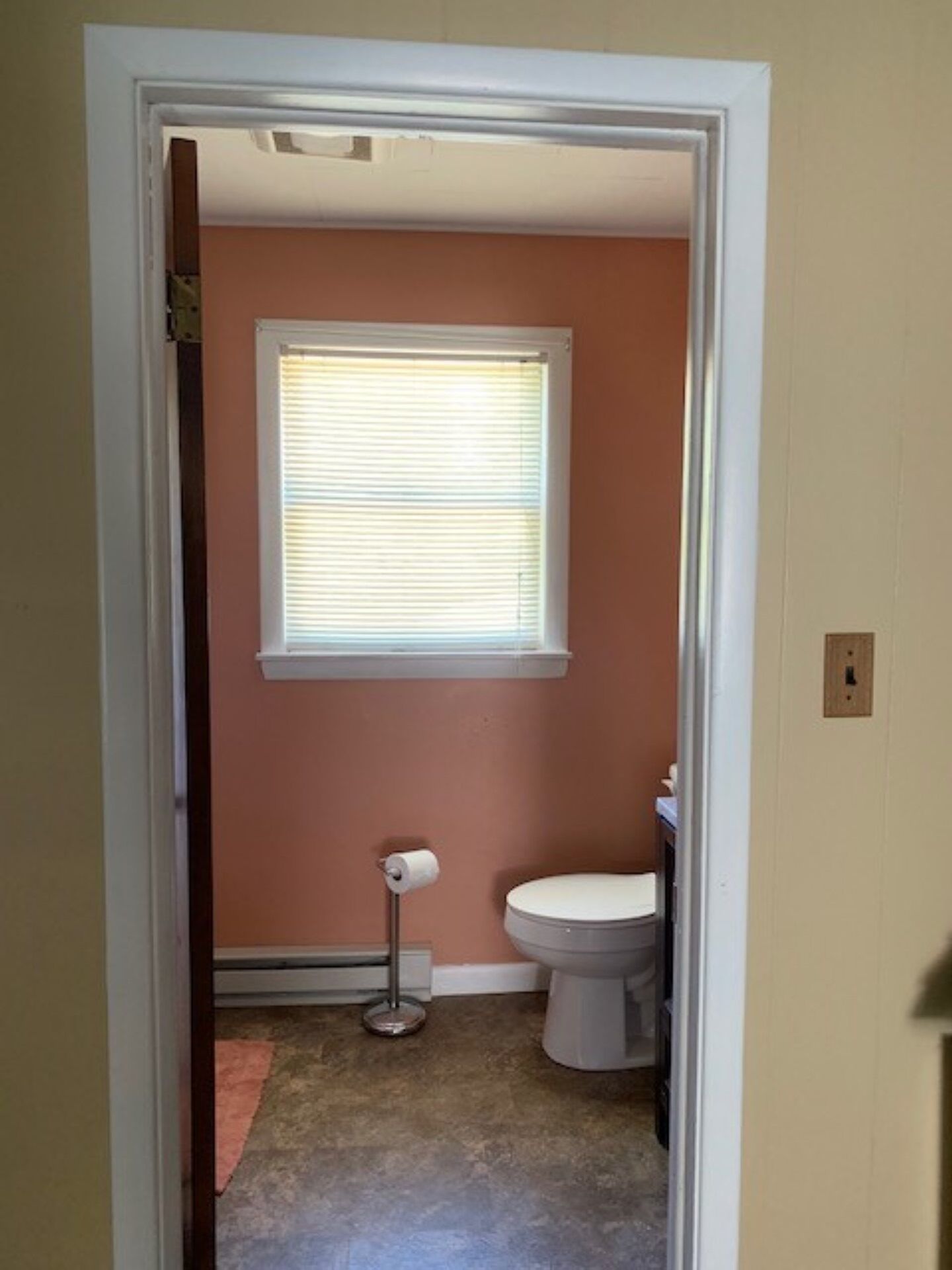 A bathroom with a toilet, a bidet, and a window with blinds.
