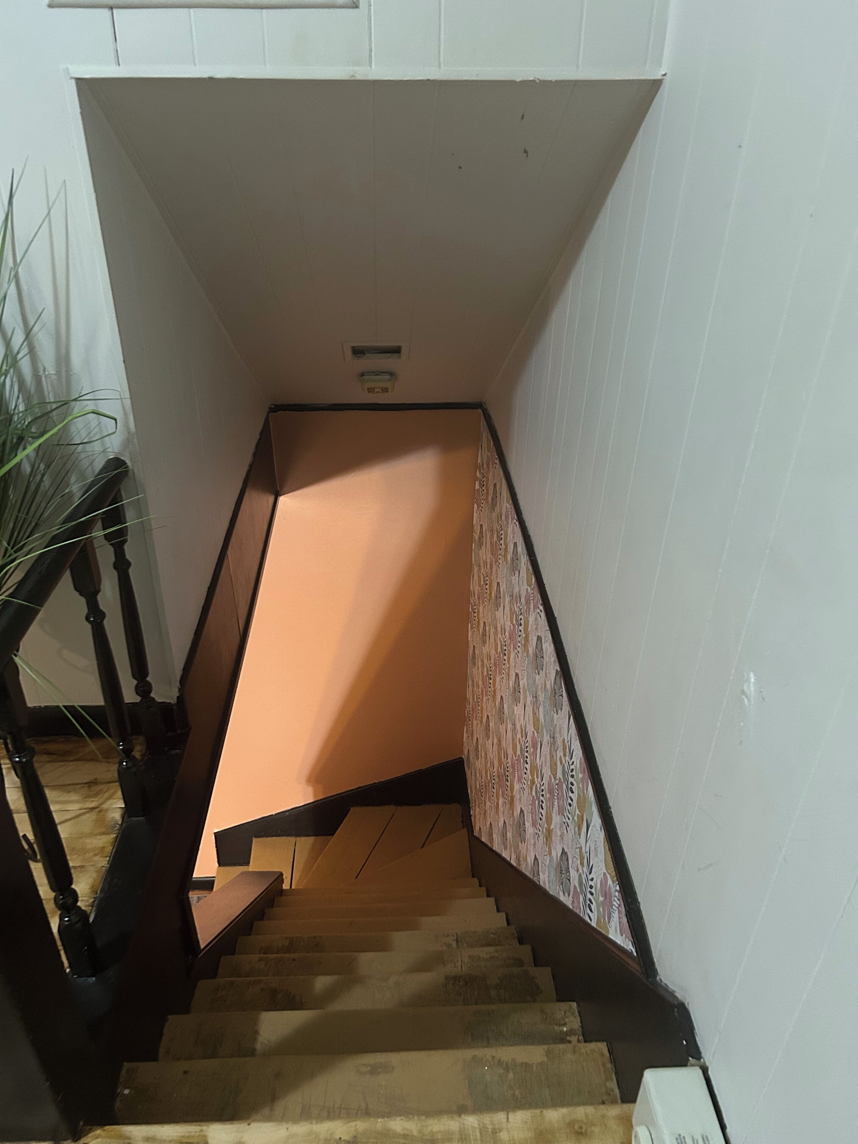 Una escala amb barana de fusta i un mur amb disseny.