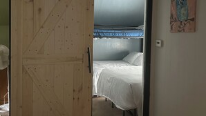 A room with a wooden door leading to a bedroom with a bed and a blue curtain. - ATV and Snowmobile right from the house !!!! (Berlin)