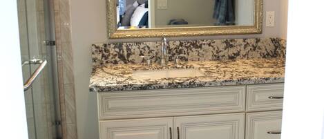 A bathroom with a marble sink, a large mirror, and a shower area.