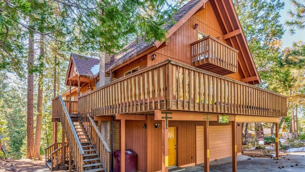 A wooden cabin with a balcony, a staircase, and a garage.