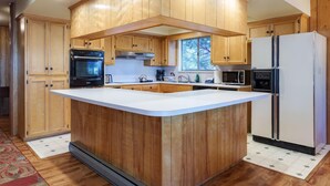 A kitchen with wooden cabinets, a central island, a refrigerator, and a microwave.