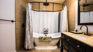 Un bagno moderno con una vasca da bagno freestanding, un mobile vanità con uno specchio e una tenda doccia.