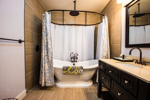A modern bathroom with a freestanding bathtub, a vanity with a mirror, and a shower curtain. - Chateau in the Vineyard (Fairfield)