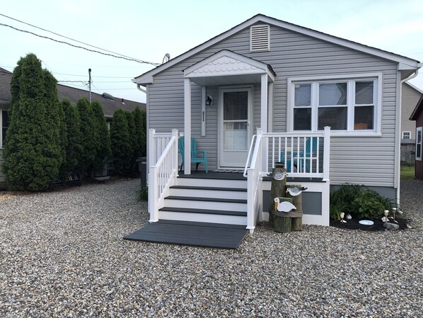 A single-story house with a porch, a set of stairs leading to the entrance, and a gravel driveway.