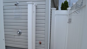 Un mur extérieur blanc avec une poignée de porte en métal et un petit cadenas rouge.