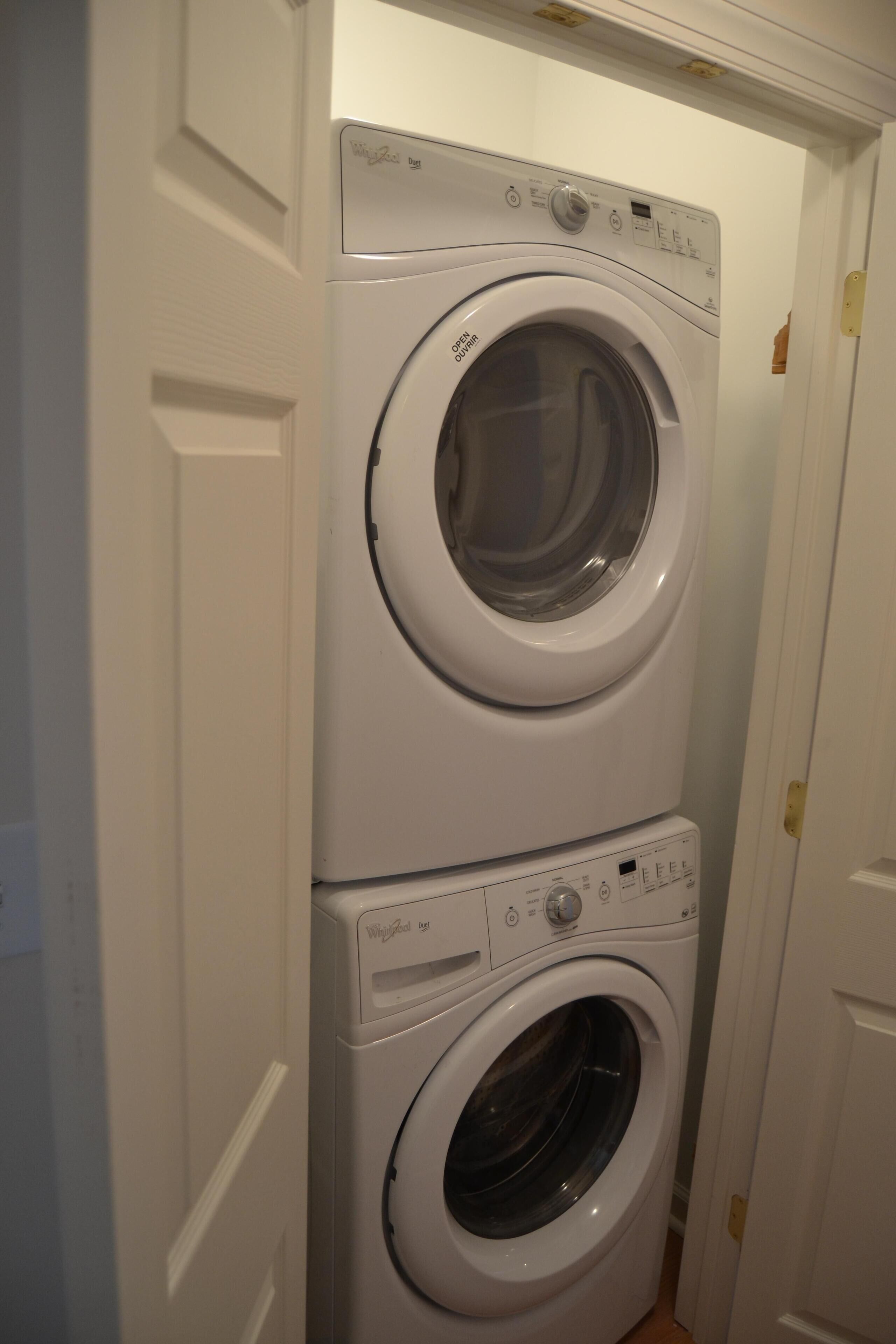 A stacked washer and dryer unit in a narrow hallway.