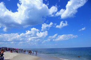 A beach with people swimming and sunbathing under a clear sky.