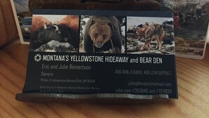 Visitekaartje voor Montana's Yellowstone Hideaway en Bear Den, met contactgegevens en een foto van een beer.