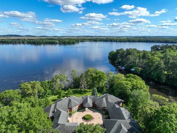 A large house with a central courtyard, surrounded by lush greenery and a lake.