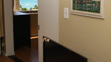A room with a view of the ocean, a framed poster on the wall, and a desk with a computer.