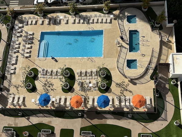 An aerial view of a resort with a large central pool, multiple smaller pools, and numerous sun loungers and umbrellas.