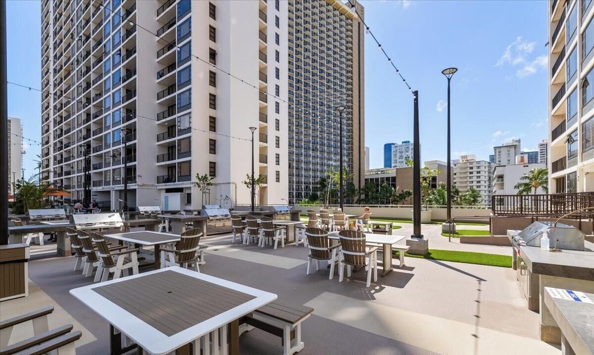 A rooftop patio with outdoor seating and a view of tall buildings.