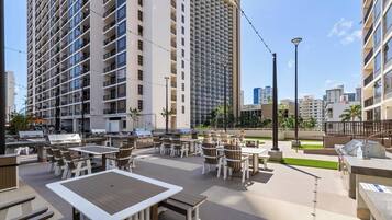 A rooftop patio with outdoor seating and a view of tall buildings.
