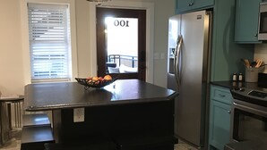 Een moderne keuken met een centraal eiland, donkere kastjes en roestvrijstalen apparatuur.