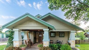 Une maison à deux étages dotée d’un porche abrité, de piliers en pierre et d’une pelouse bien entretenue.