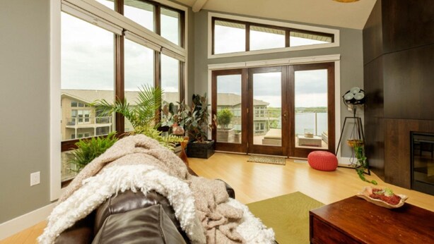 Un salón amplio con ventanas grandes, una chimenea y vistas a un cuerpo de agua.