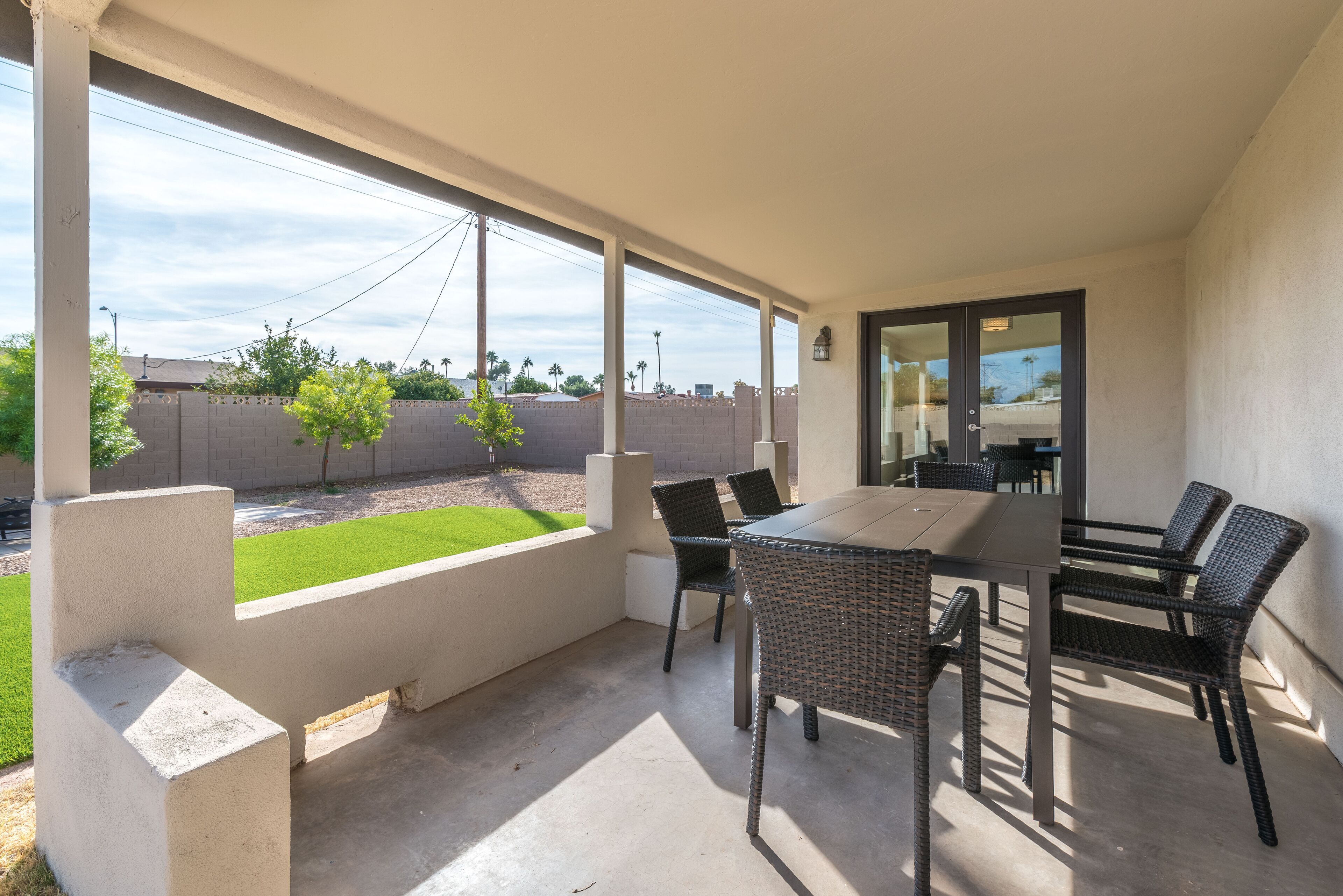Portico coperto con tavolo e sedie, vista sul giardino e una porta che dà all'interno.