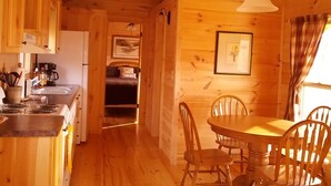 L’intérieur d’un chalet en bois comprend une cuisine, un coin repas et un lit.
