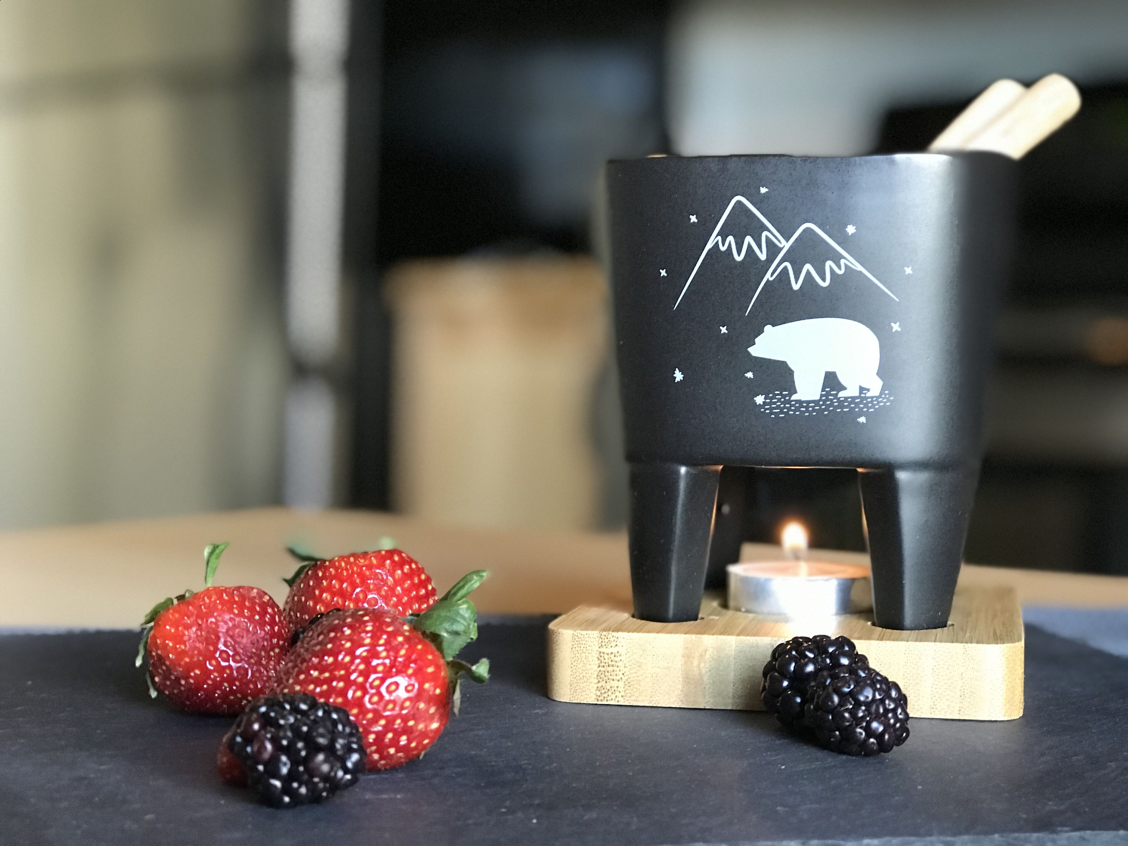 Un chandelier orné d’un motif représentant un ours et une montagne, entouré de fraises et de mûres.