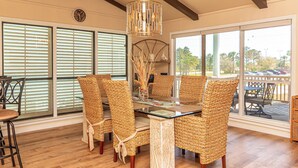 Un comedor con sillas de mimbre, una mesa con cubierta de vidrio y una lámpara decorativa.