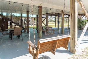 Relax in a serene outdoor space with a wooden swing, picnic table, and comfortable seating area.