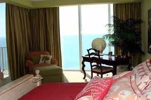 Relax in this serene hotel room with a large bed, ocean views, and a cozy reading nook.