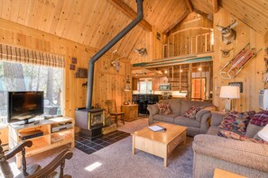 A cozy cabin interior with a fireplace, wooden walls, a sofa, and a television. - Icicle Riverhaus-Cozy Riverfront Cabin Leavenworth (Leavenworth)
