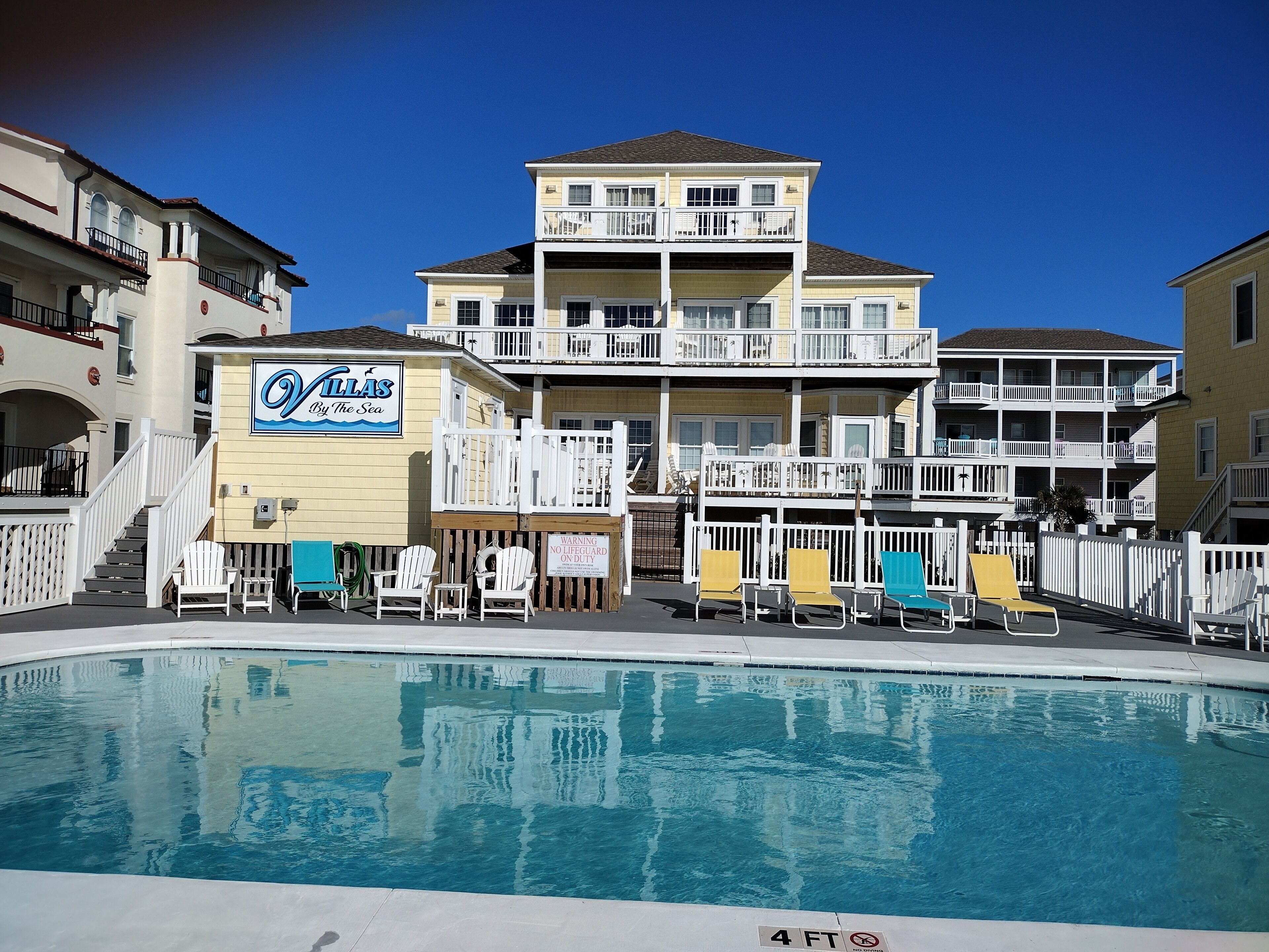 A hotel with a pool, multiple balconies, and outdoor seating.