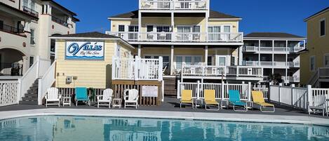 A hotel with a pool, multiple balconies, and outdoor seating.