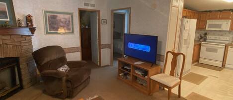 A living room with a fireplace, a television, and a kitchen area with a microwave and oven.