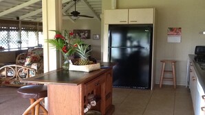 Uma cozinha com geladeira preta, balcão de madeira e ventilador de teto.