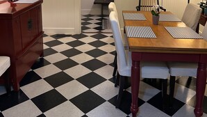 A dining area with a checkered floor, a wooden table with placemats, white chairs, and a painting on the wall. - Lavender House Cottages, Classic Elegance in a Country Cottage (Point Reyes Station)