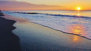 A beach at sunset with waves gently lapping the shore. - "Chasing Waves"-Oceanfront Luxury King Condo w/ Kitchen, Living Room & that View (Myrtle Beach)