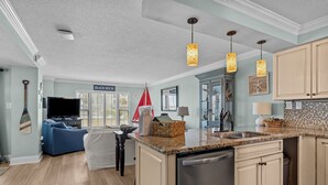 A modern kitchen with a central island, built-in appliances, and pendant lighting. - Oceanfront! Private Beach Access. Prime location, building A-main pool & complex (Indian Beach)