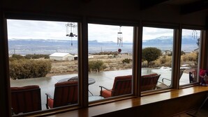 A room with large windows offering a view of a mountainous landscape and a distant city. - Little Park Road Retreat - Hot Tub with a View (Grand Junction)
