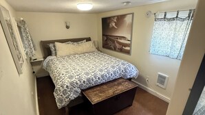 Un dormitorio con cama, cómoda, ventana con cortinas e imagen colgada en la pared.