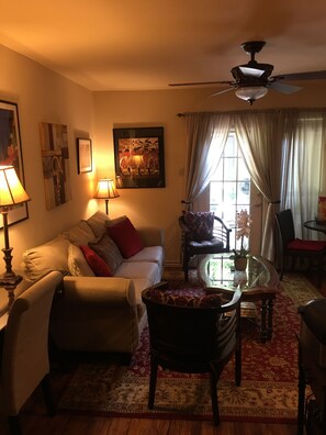 A cozy living room with a sofa, armchairs, a coffee table, and a ceiling fan.