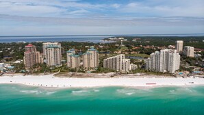 A coastal cityscape with high-rise buildings, a beach, and a clear view of the ocean.