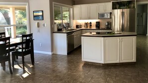 A modern kitchen with white cabinetry, a central island, and a dining area with a table and chairs.