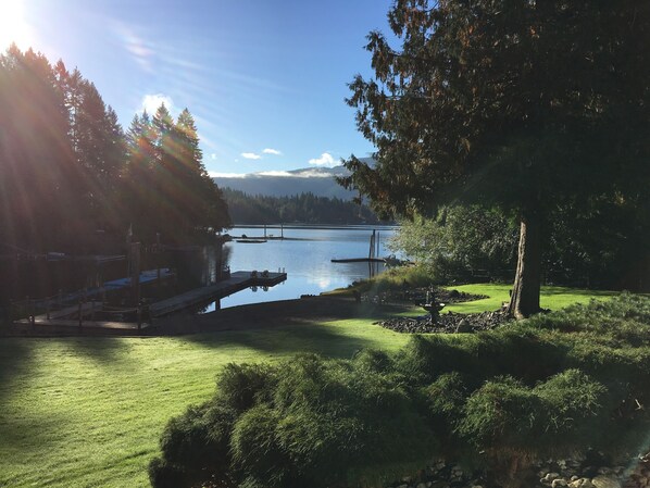 Vista de un lago con muelle, zonas verdes y árboles.