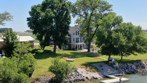 A house with a large lawn, a dock extending into a body of water, and a stone wall. - Huge Lakefront House - sleeps 22! Private Dock! Boating, Water Skiing, Rafting! (Heyburn)