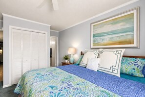 Une chambre à coucher avec un lit, une table de chevet, une lampe, un tableau et une armoire.