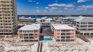 A beachfront hotel with multiple buildings, a central pool, and a view of the ocean.
